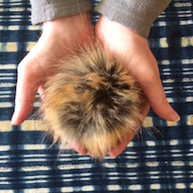 hands holding fluffy faux-fur pompom